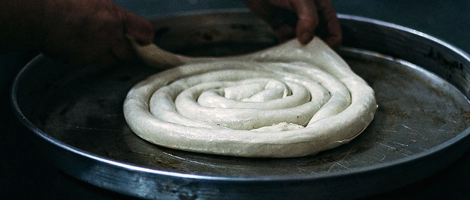 Ruke slažu namotanu koru u okruglu tepsiju